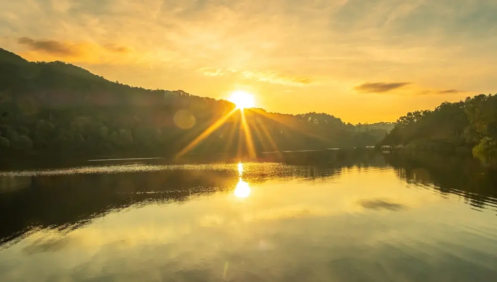Sunset casting orange light over a calm river lined with trees